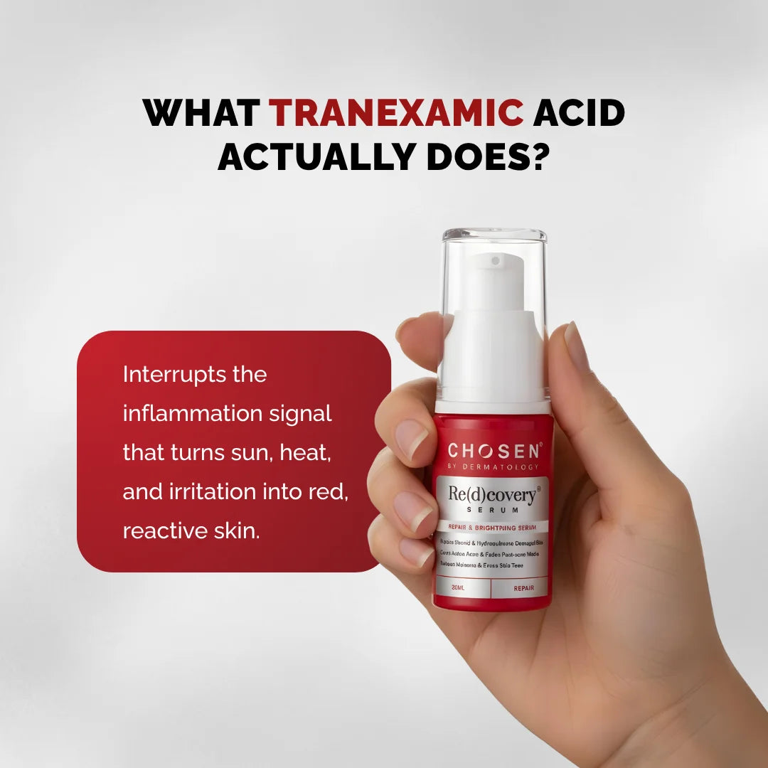 Hand holding a red and white skincare bottle with text about tranexamic acid on a gray background