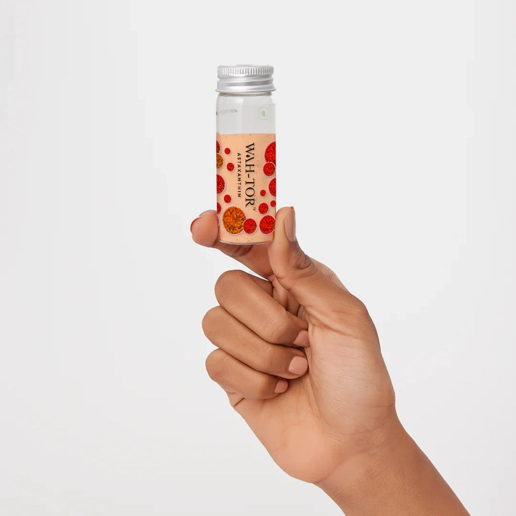 Hand holding a bottle of Astaxanthin powder for skin health